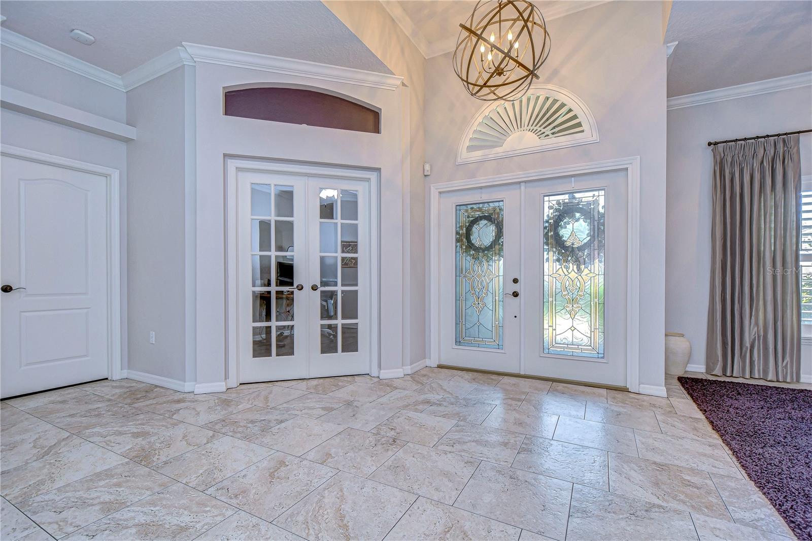 Step into elegance with this welcoming entryway featuring grand double doors and stylish tile flooring.