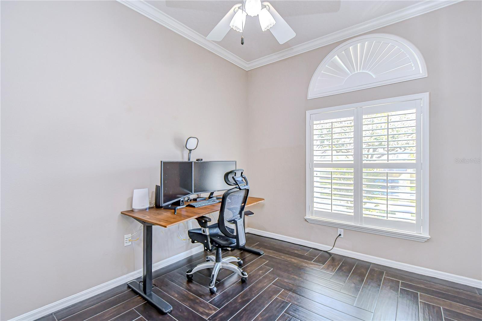 A sunlit home office space , featuring elegant plantation shutters and sleek wood look porcelain flooring.