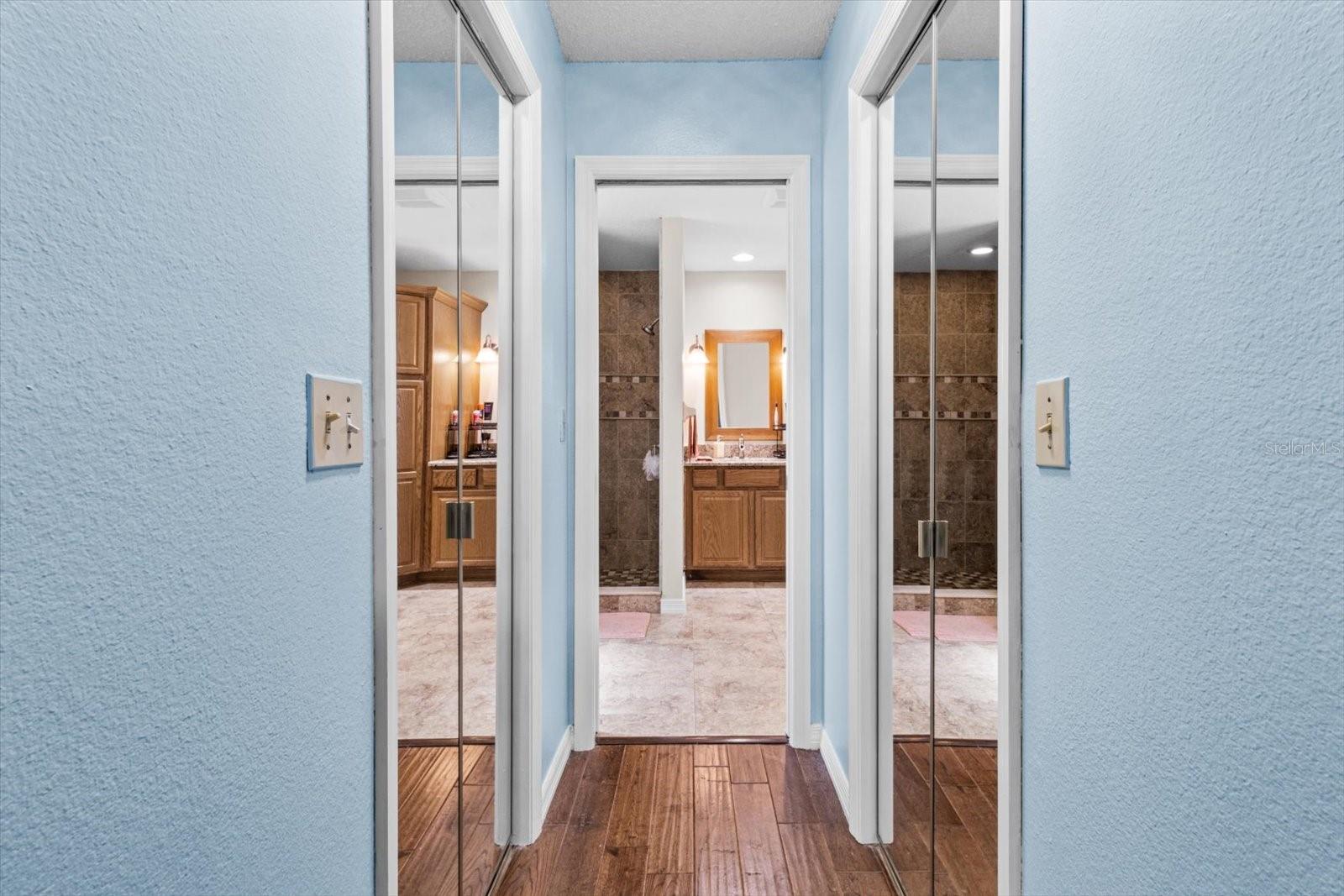 Hallway to master bath with his and her closet