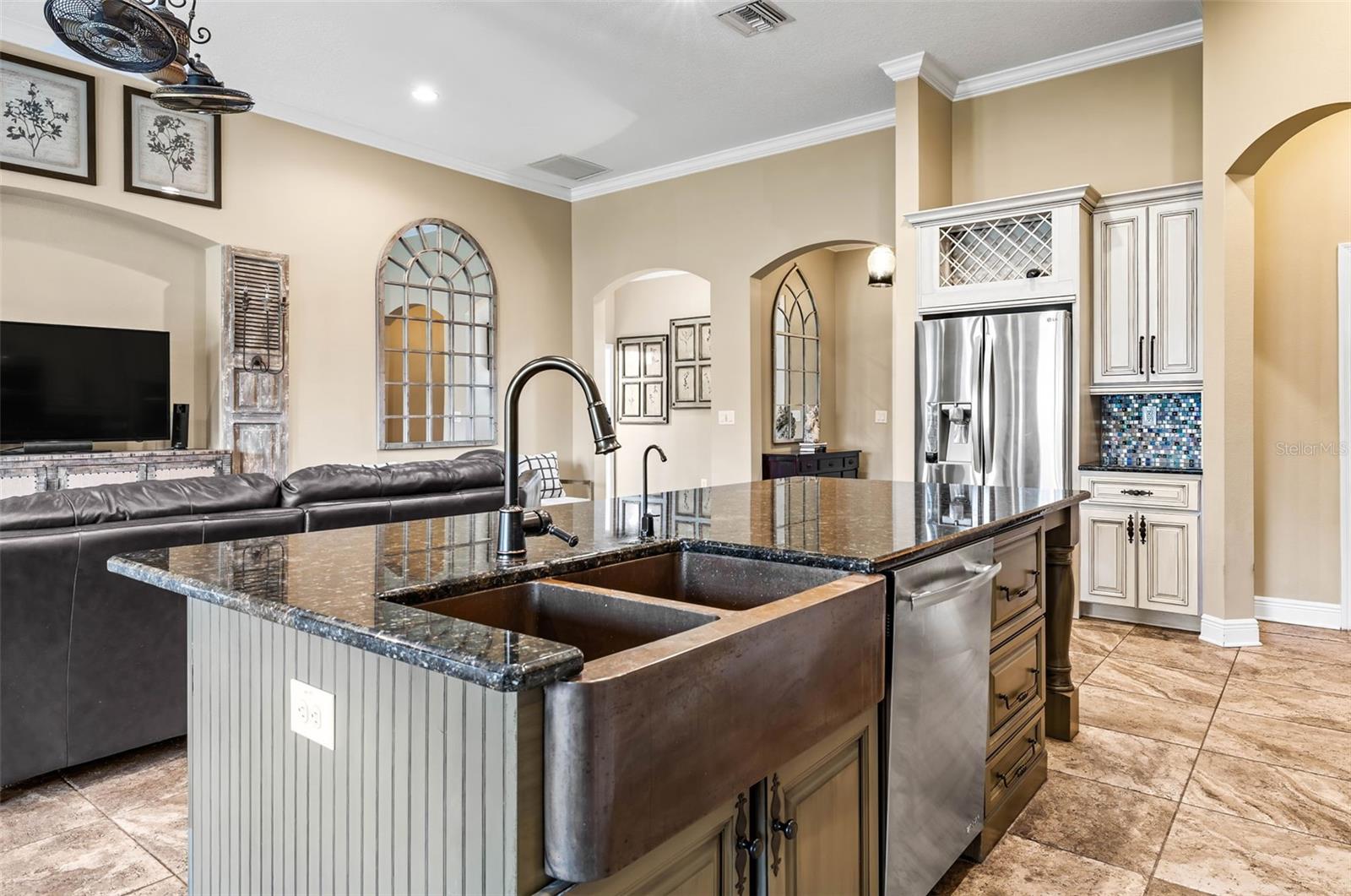 Large island that serves as a casual dining space with copper colored sink.