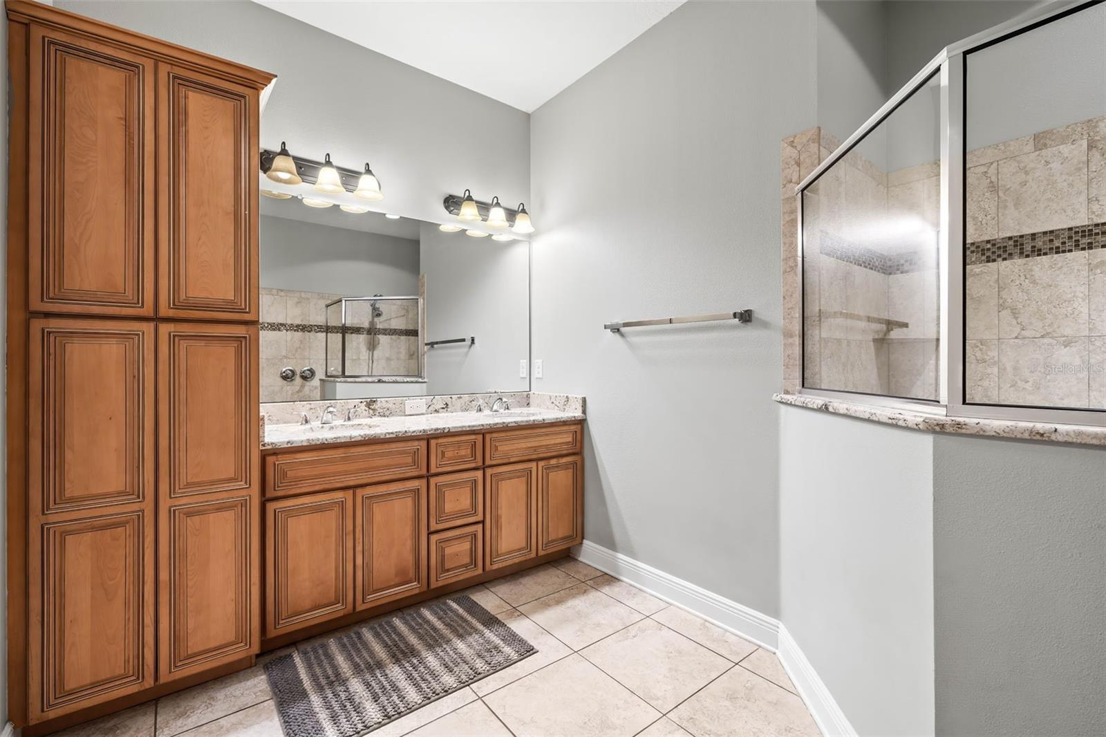 Primary bathroom vanity featuring dual sinks and lots of wood cabinets with crown olding detail.