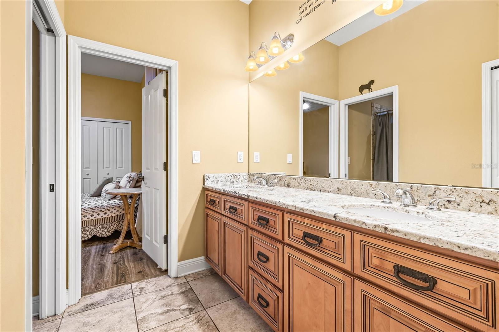 Jack and Jill bathroom situated between bedrooms 3 and 4. Granite countertop and wood cabinets.