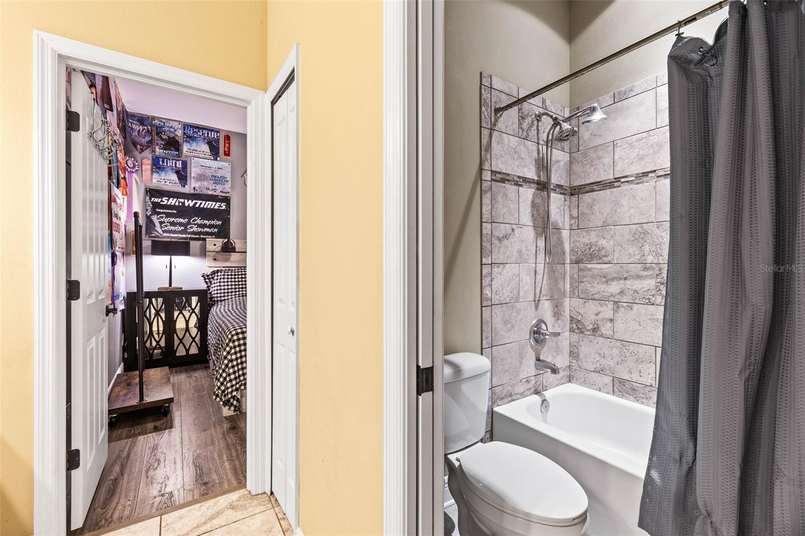 Jack and Jill Bathroom has separate toilet and shower area. Provides a tub/shower combination with large showerhead and decorative tile.