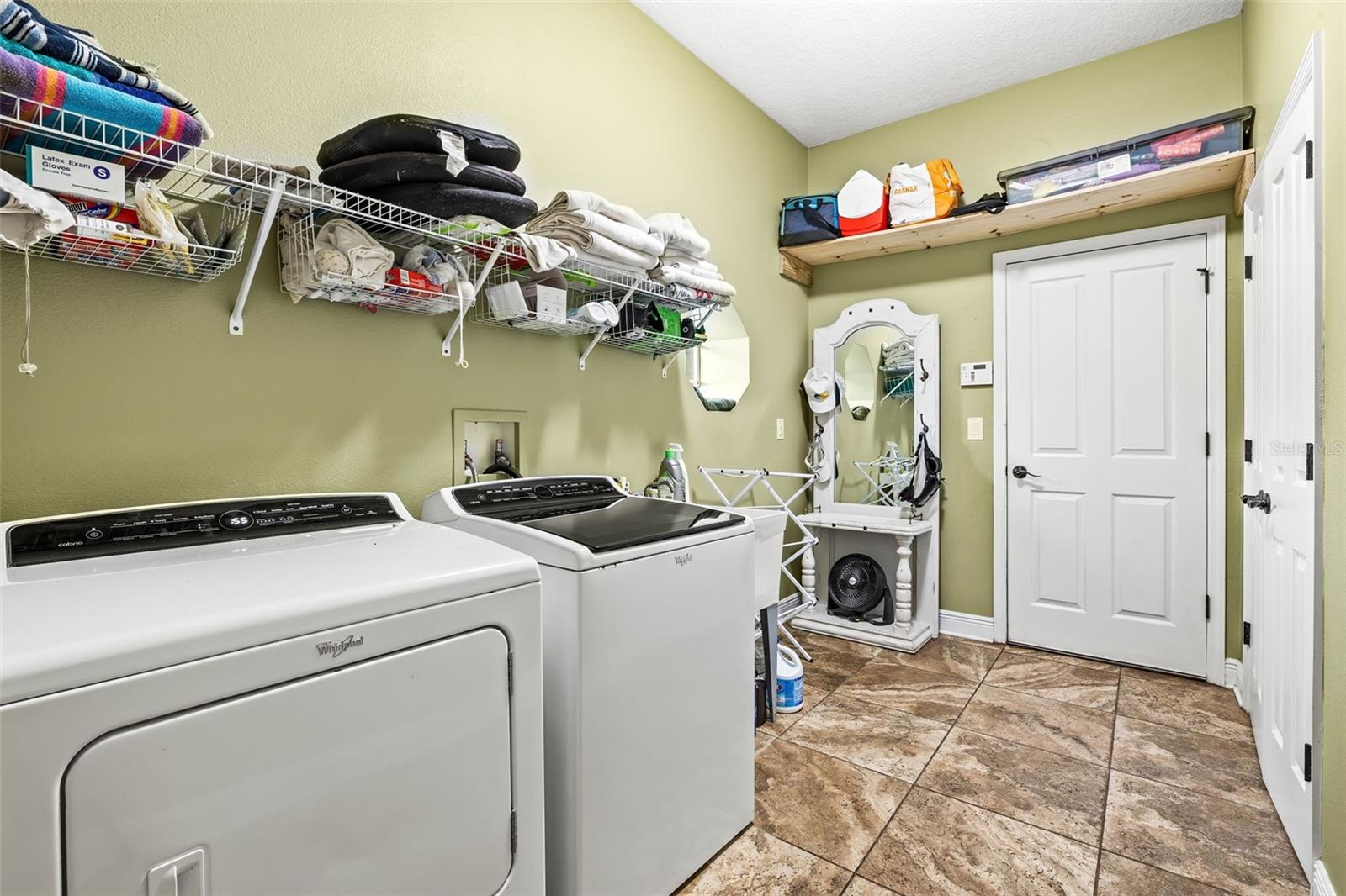 Laundry room complete with washer, dryer sink and shelving. Located off of the garage.