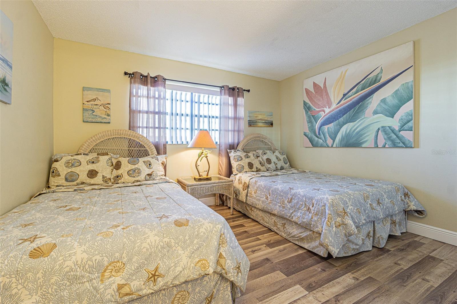 The second bedroom has two twin beds with wood-like flooring.