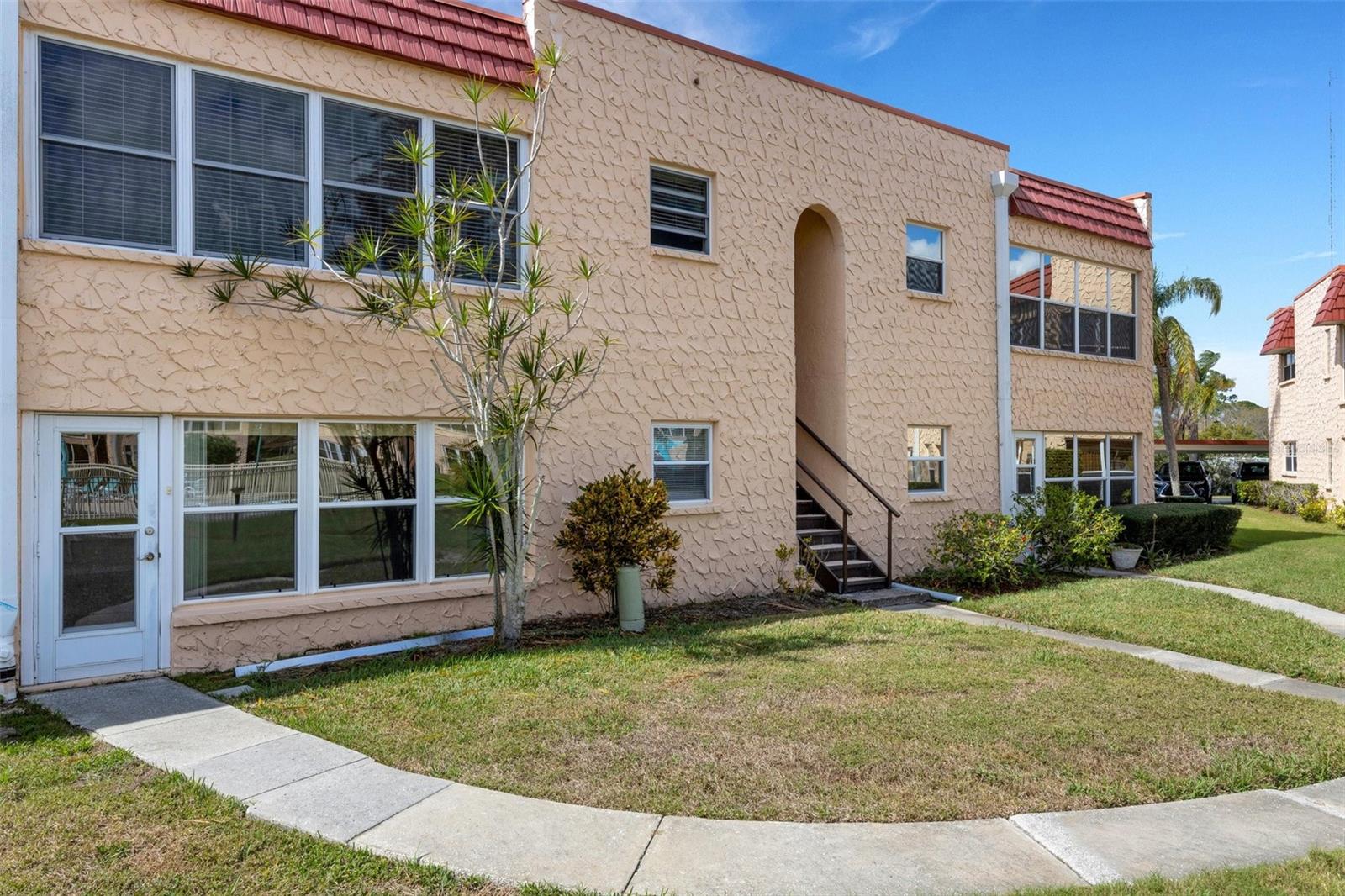 Back of Unit with Pedestrian Door and Sidewalk to Pool and Clubhouse