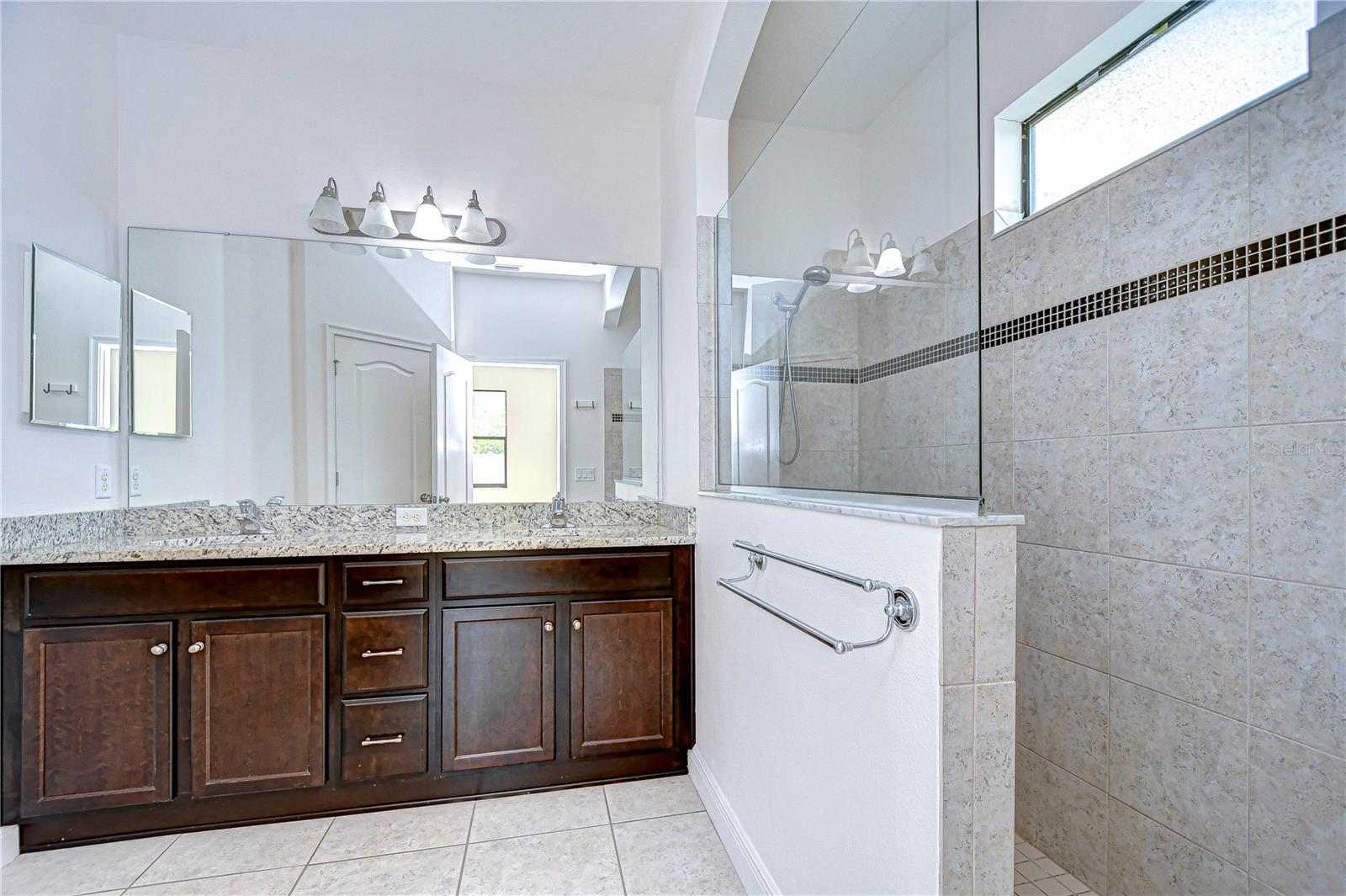 elegant bathroom featuring a spacious double vanity and sleek glass shower.