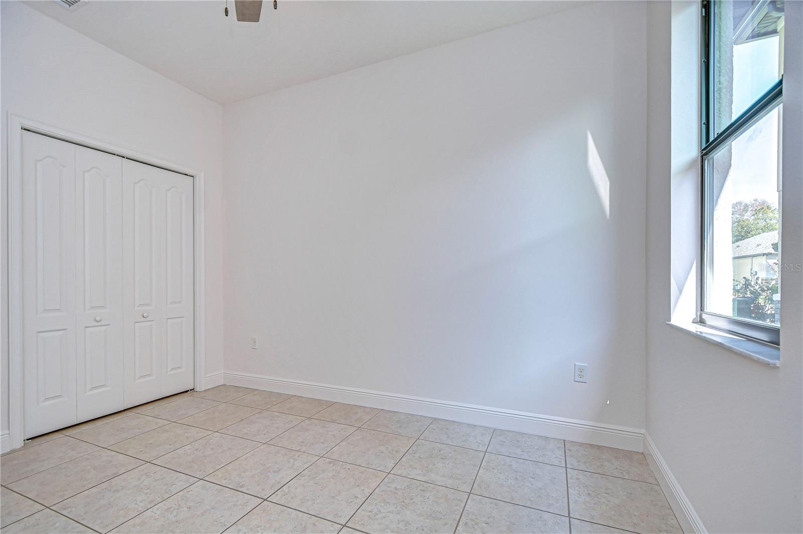 Bright and airy third bedroom with tile flooring.