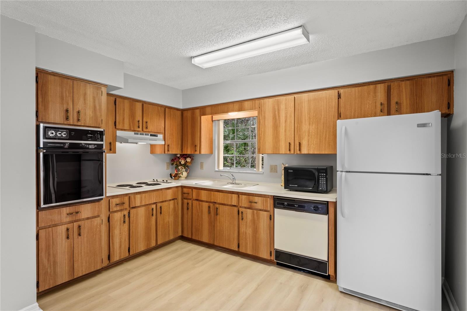 Oak kitchen cabinets, double sink, cooktop, wall oven, dishwasher, garbage disposal and refrigerator.