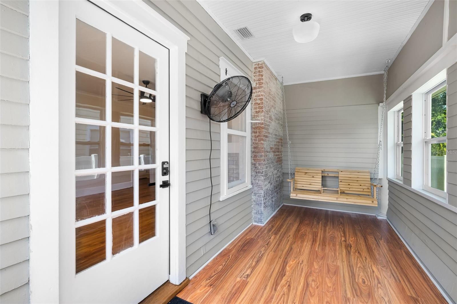 Front sun room with wooden bench swing for two.