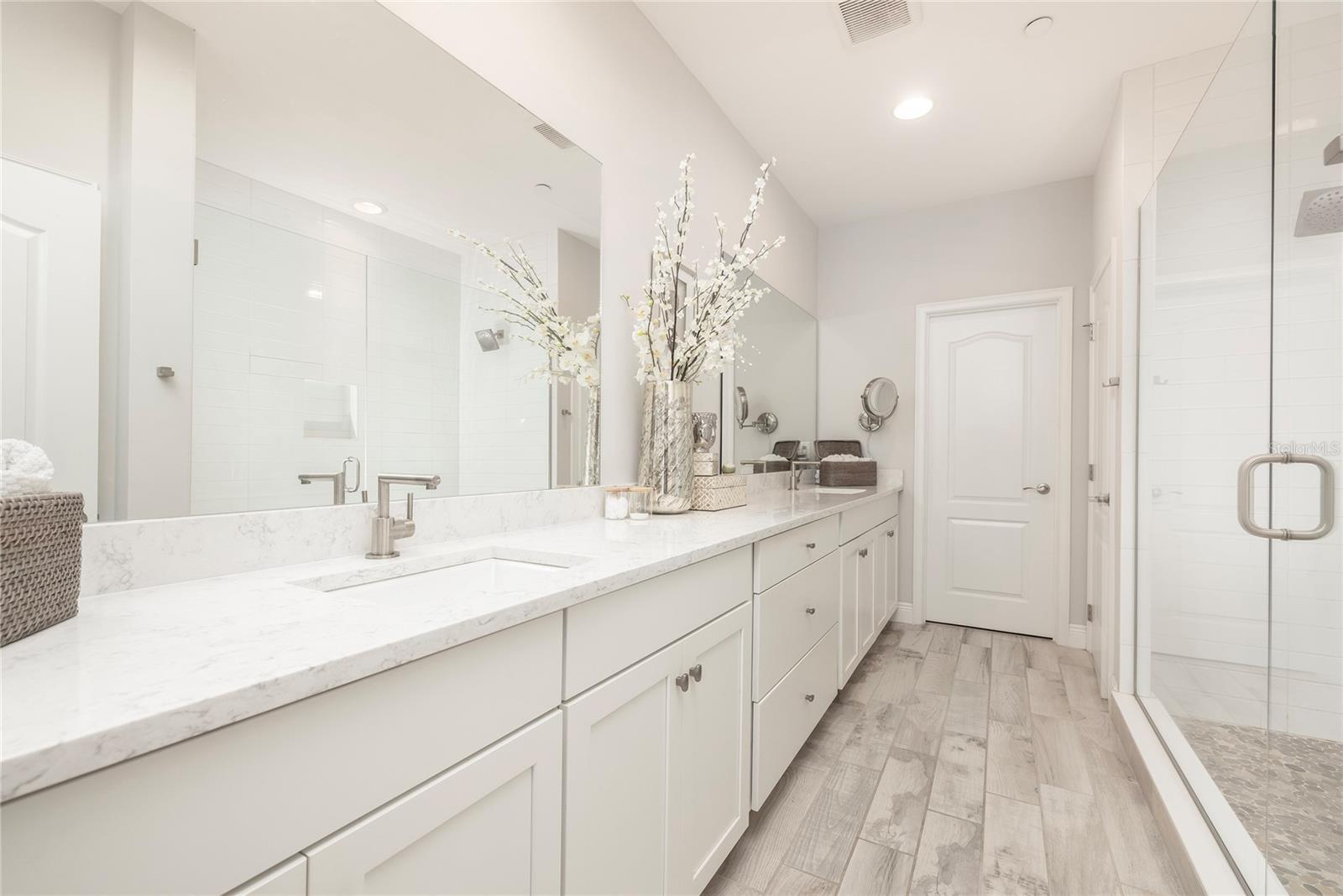 Large Primary Bathroom with dual sinks, oversized shower and access to second walk-in closet