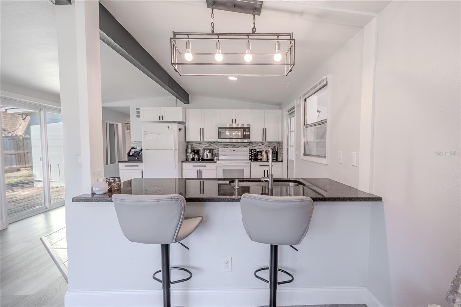 The breakfast bar and sink area are illuminated by a Linear farmhouse chandelier