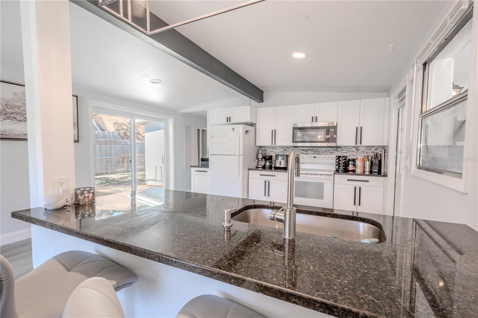 The kitchen features granite countertops and a stylish backsplash