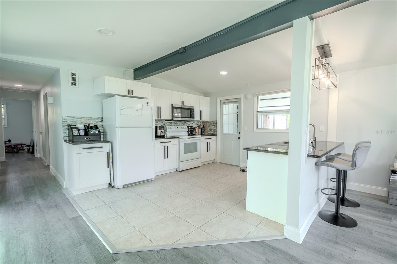 The open concept kitchen features a tile floor, recessed lighting, a full suite of appliances and a breakfast bar.