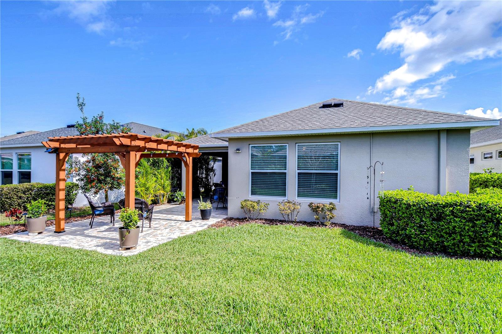 This charming backyard oasis invites you to unwind under a stylish pergola, perfect for morning coffee or sunset chats.