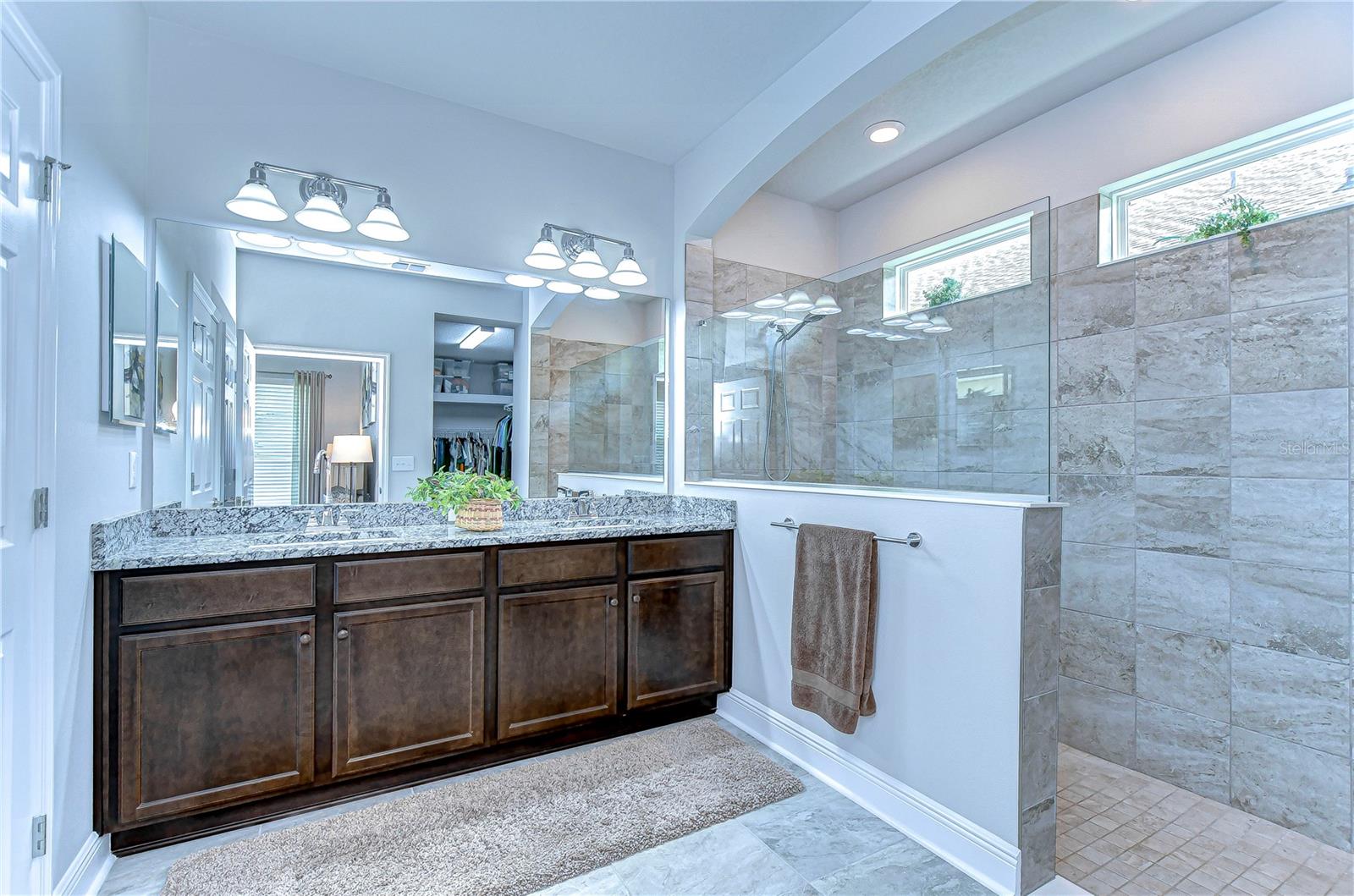 Step into tranquility with this luxurious bathroom, featuring elegant granite countertops and an expansive shower.