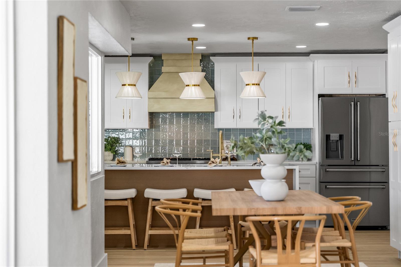 View of kitchen from dining area to the custom range hood and island design