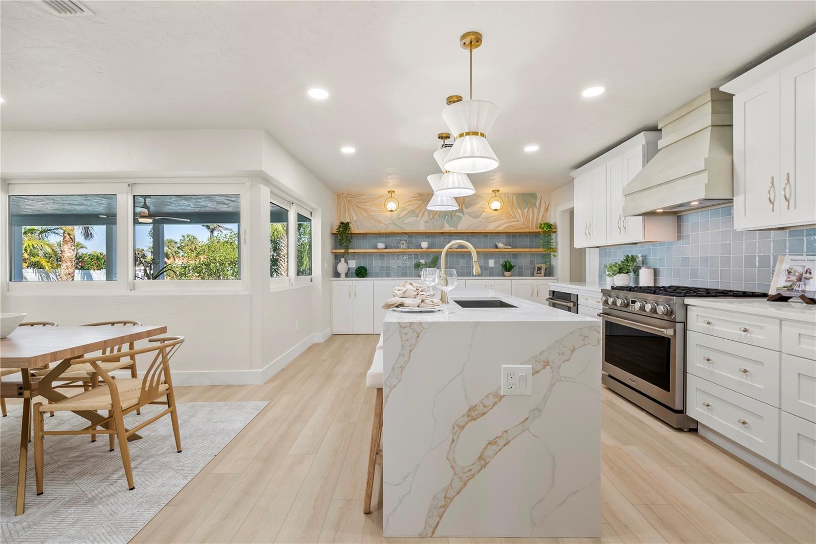 Stunning view of custom waterfall island design with view of range and kitchen cabinet design