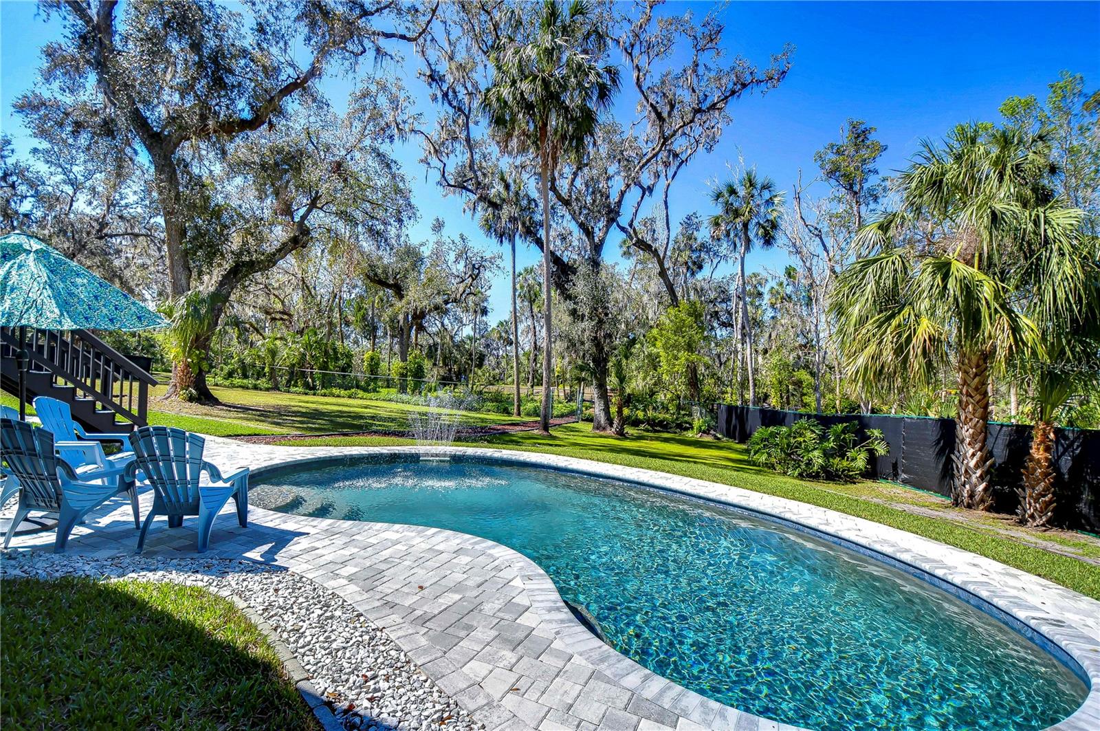 Dive into relaxation in this stunning backyard oasis, featuring a shimmering pool nestled among lush greenery.