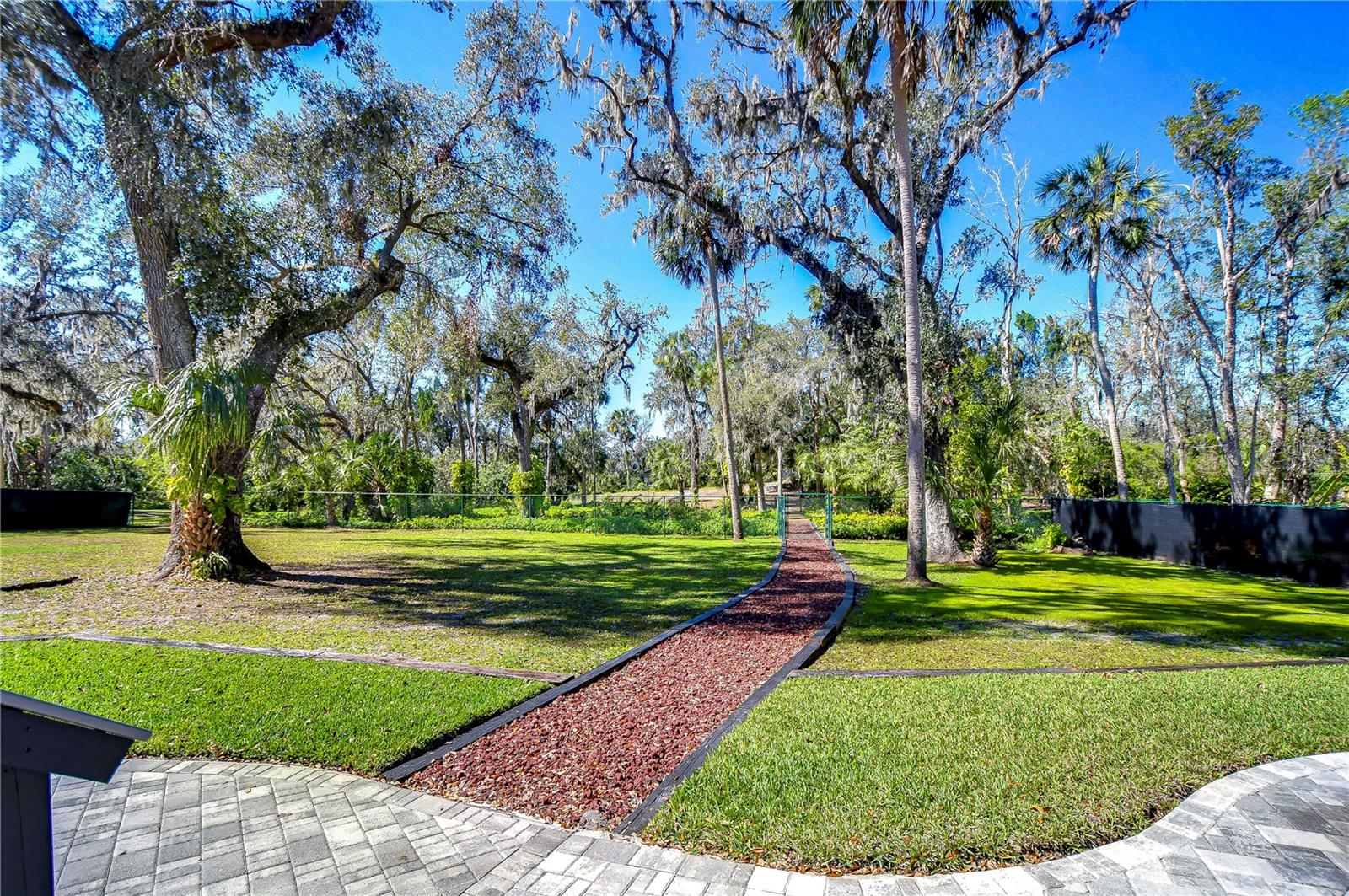 Escape to your own lush retreat with this expansive backyard, offering a serene path through mature trees and vibrant greenery