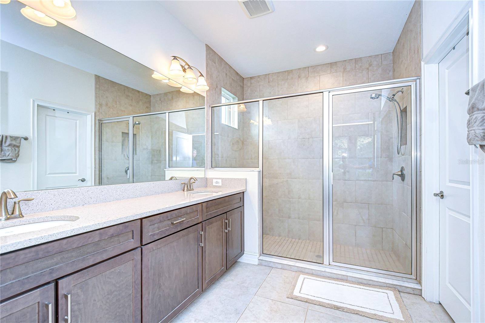 Indulge in the refined elegance of this expansive bathroom, featuring a sleek double vanity and a spacious glass-enclosed shower.