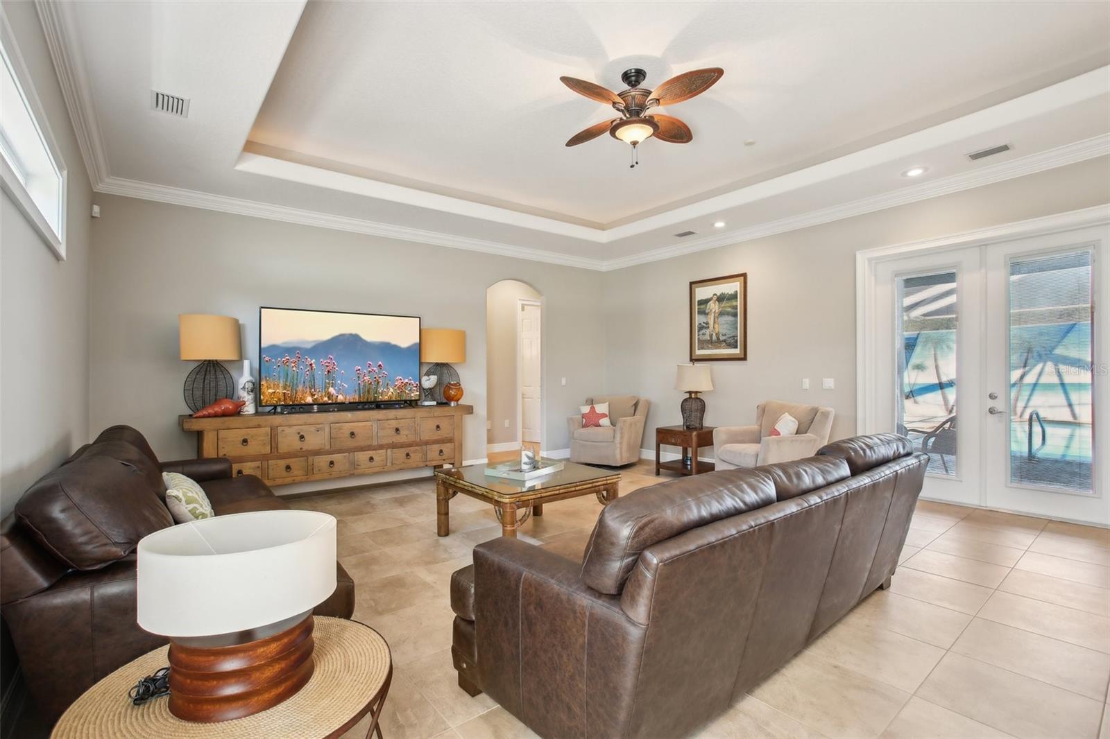 Family room with tray ceiling, beautiful natural lighting, French doors to pool area