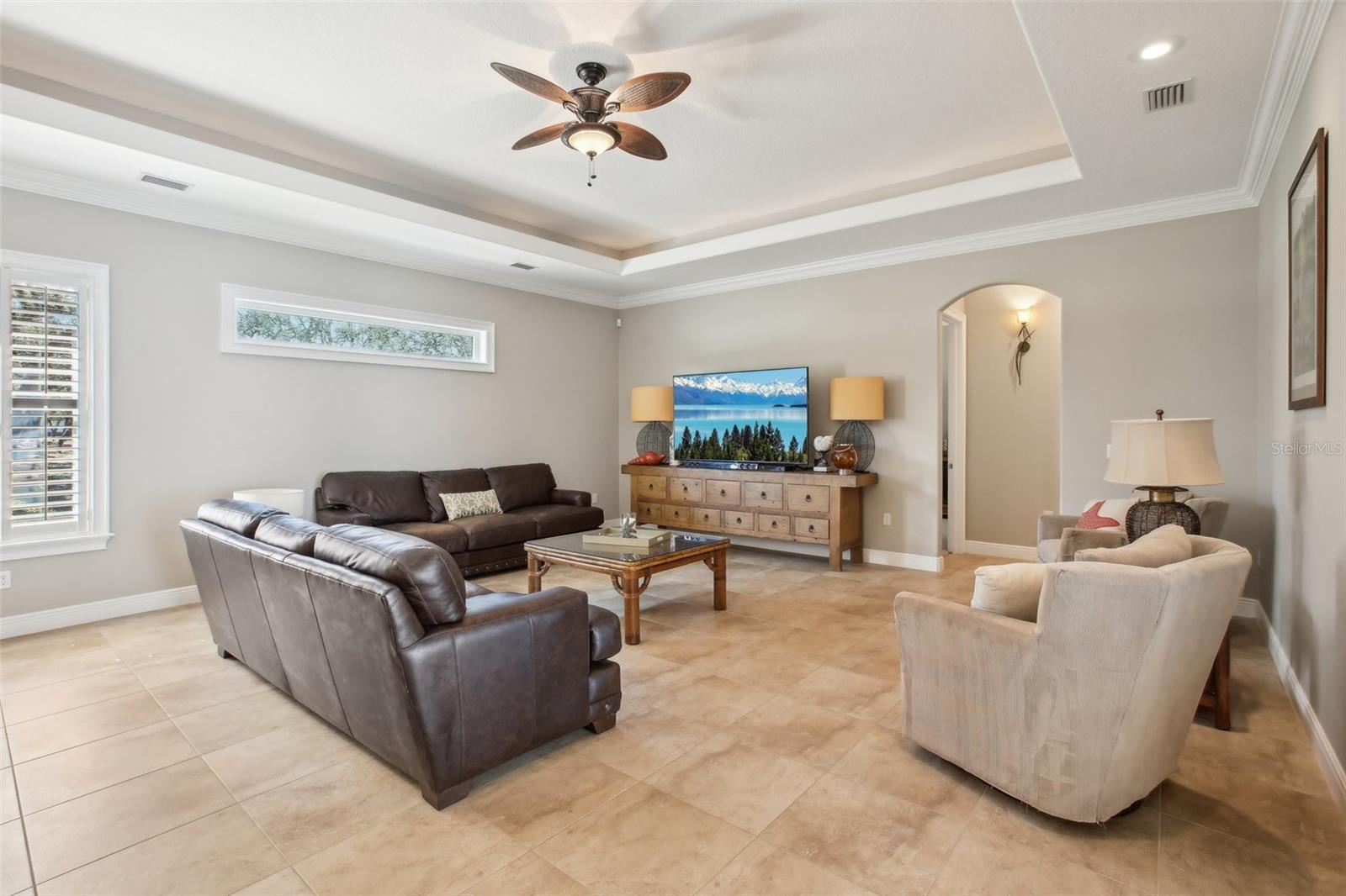 Family room with tray ceiling, beautiful natural lighting, French doors to pool area.  Hall entry to primary bedroom and guest bath and bedroom 2