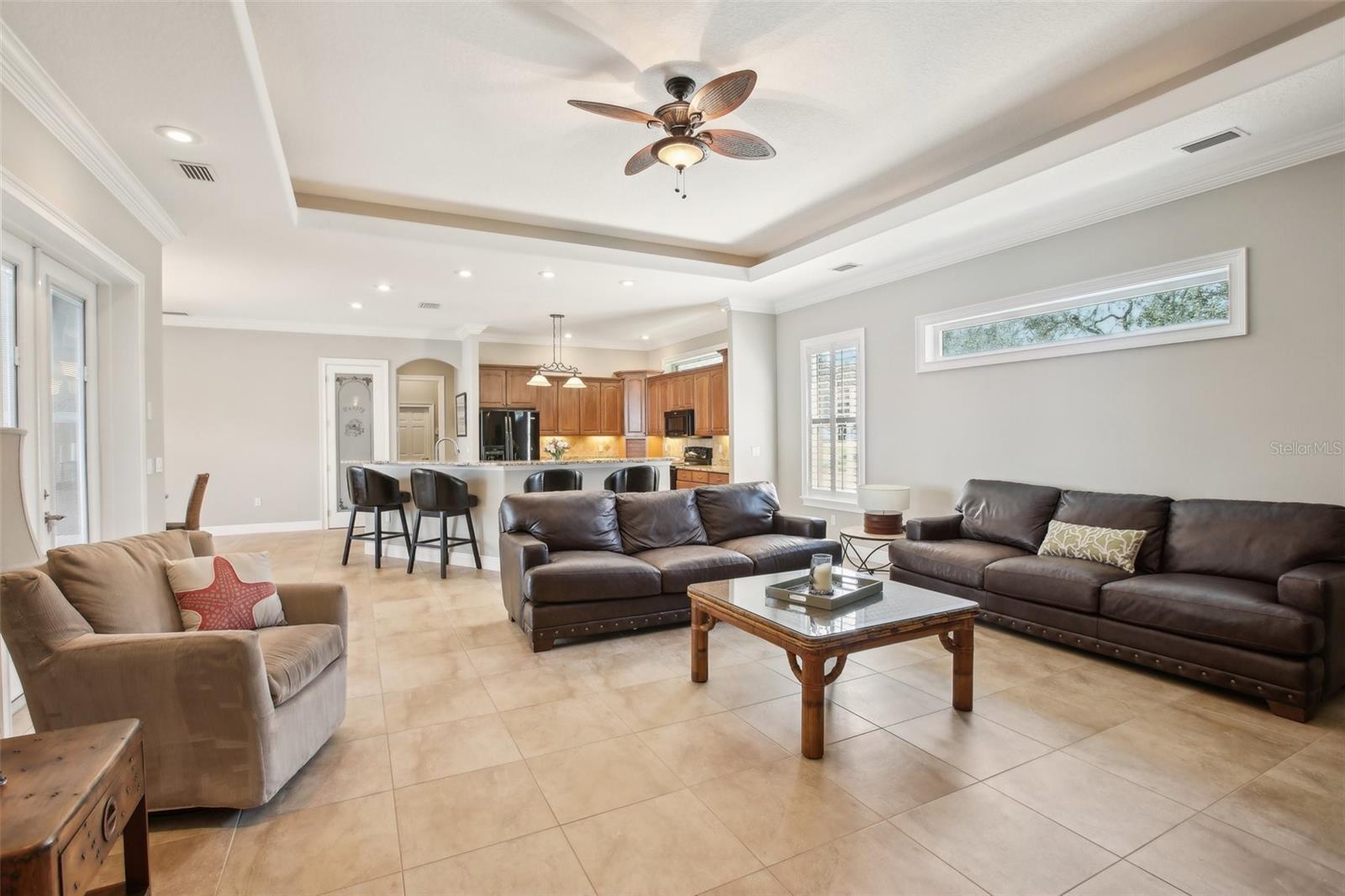 Family room with tray ceiling, beautiful natural lighting, plantation shutter and French doors to pool area