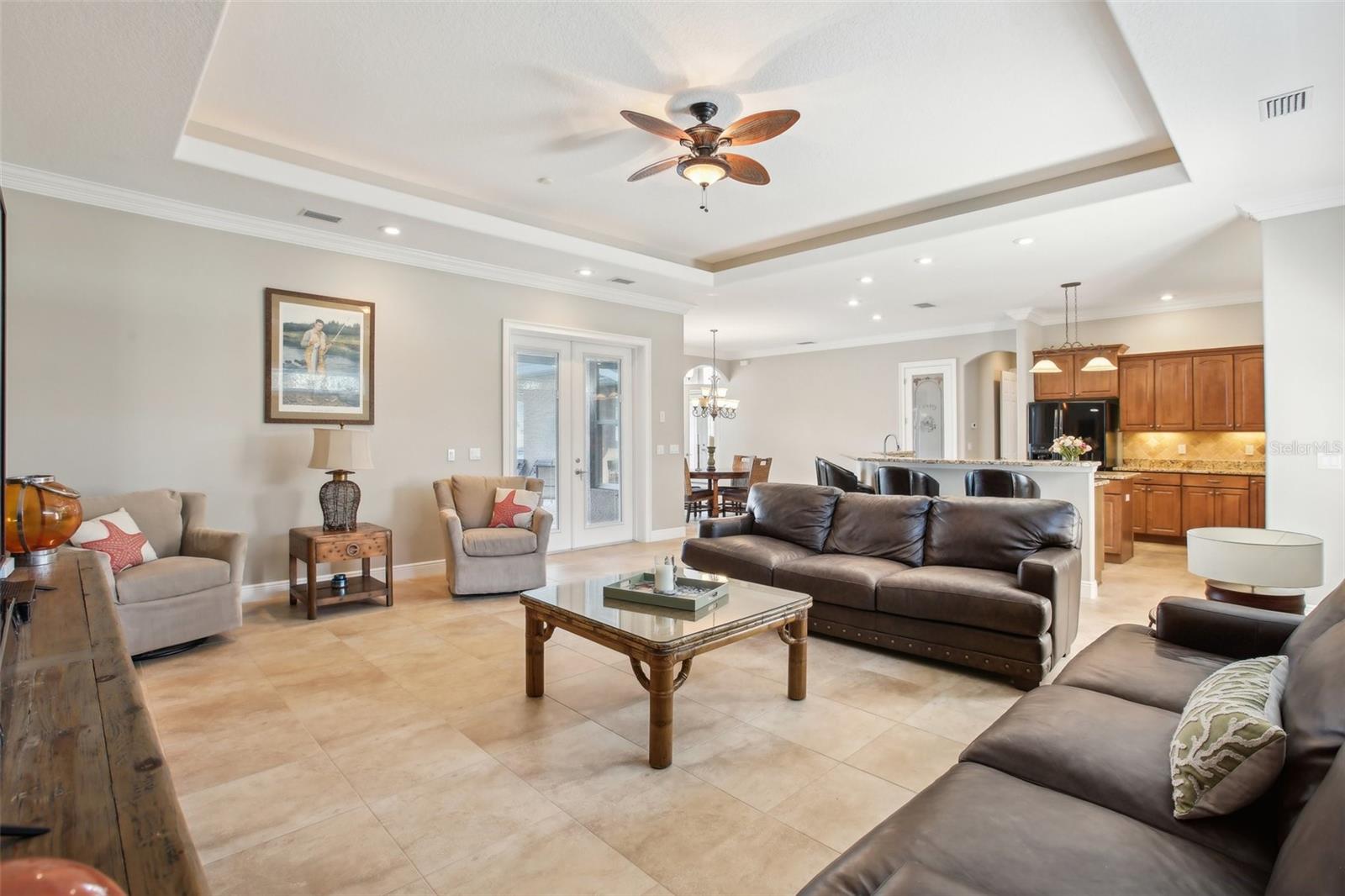 Family room with tray ceiling, beautiful natural lighting, French doors to pool area