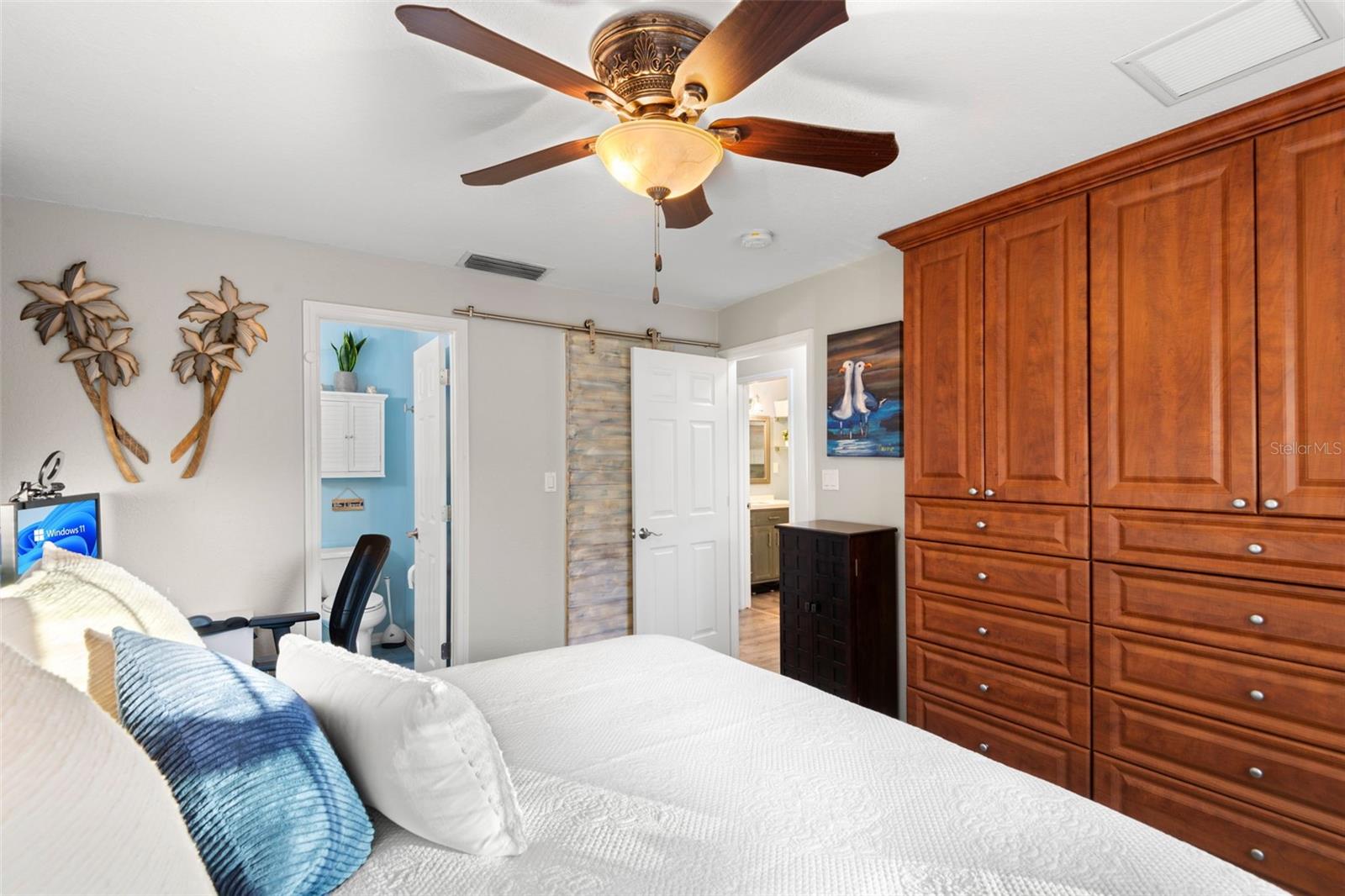 Custom wall of closet storage with hideaway TV mount in primary bedroom.