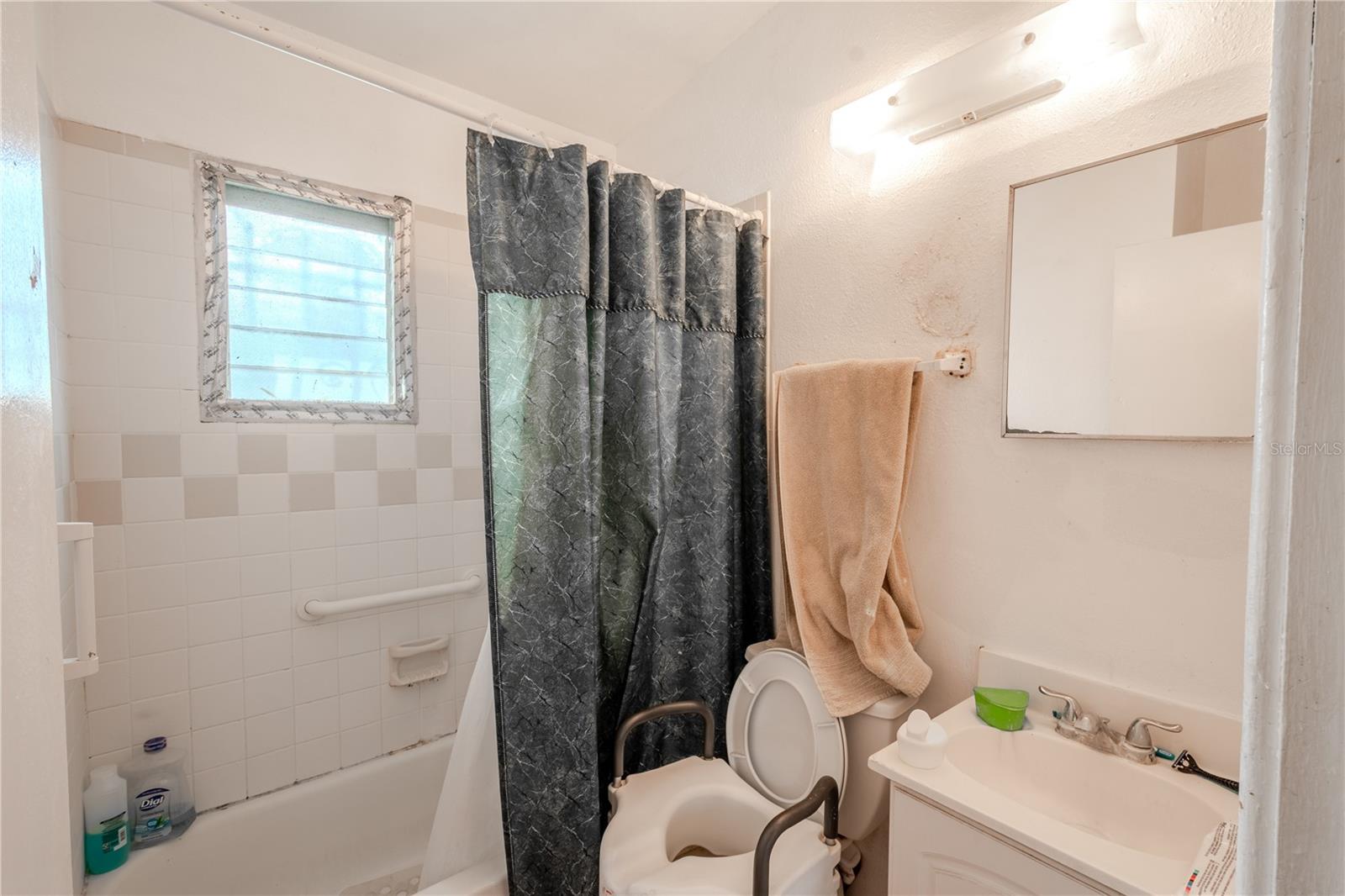 Unit 1 -Bathroom has a tile tub with shower, and a mirrored vanity with storage.