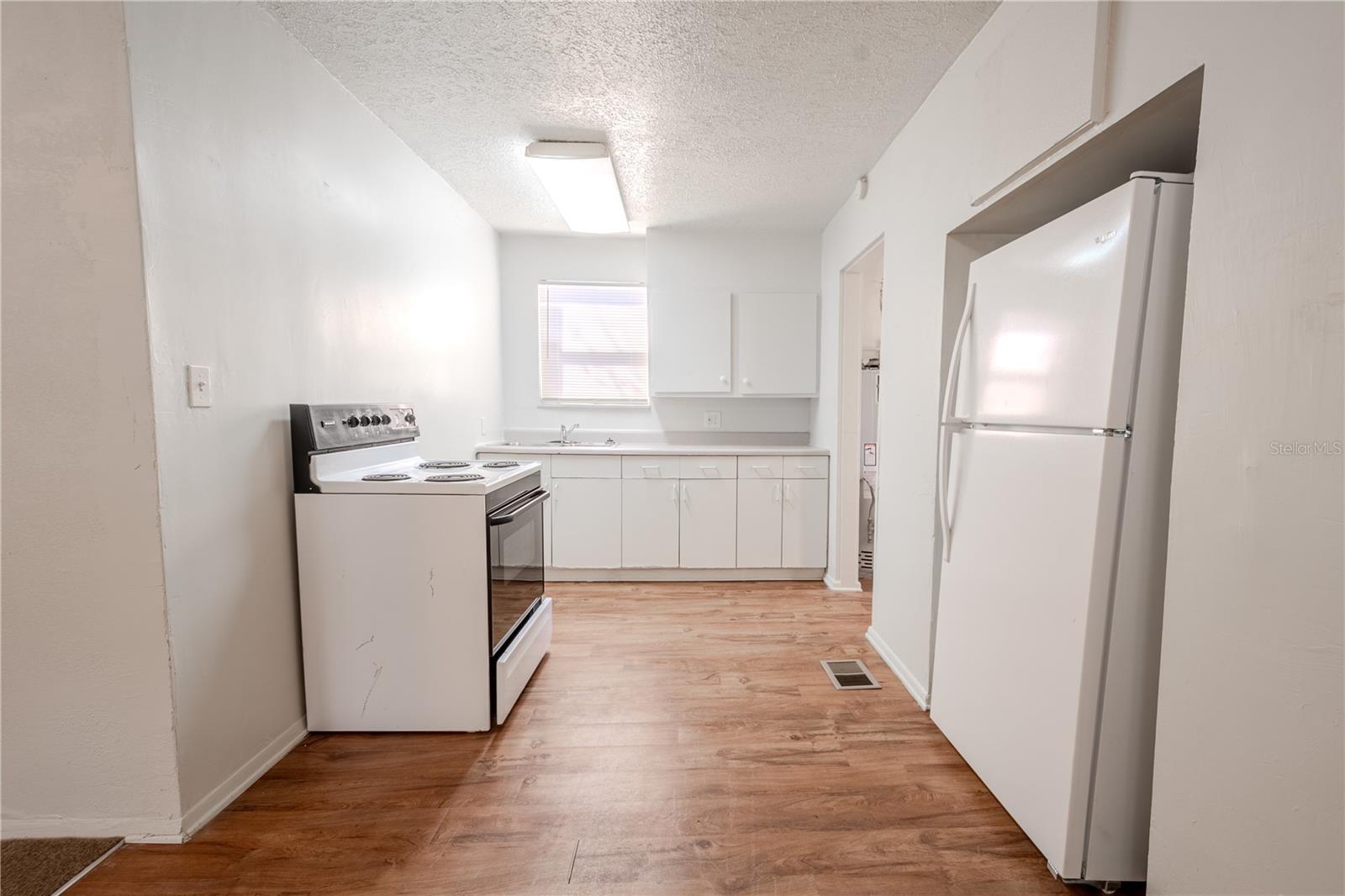 Unit 2 - kitchen has laminate floor, refrigerator and range.