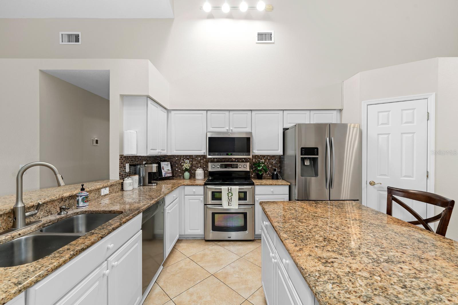 The kitchen is very spacious and features all stainless appliances, granite countertops, a double oven, cathedral ceilings, and an island with storage, electric, and seating, a newer faucet, and a walk-in closet!