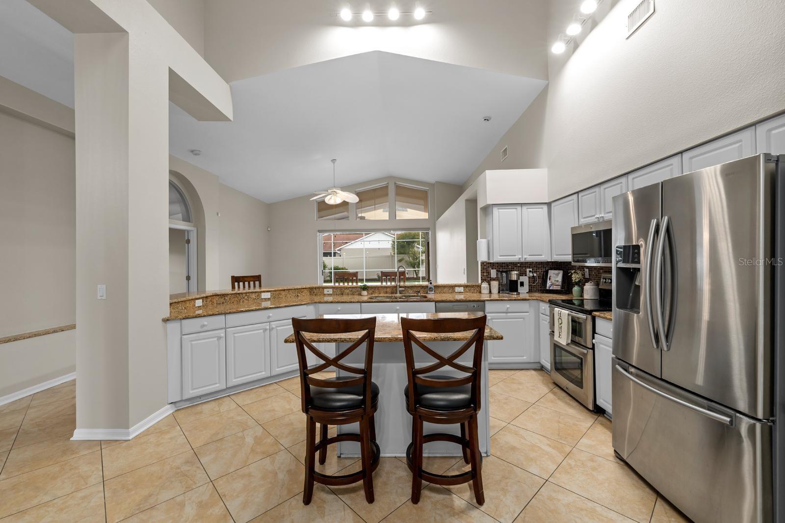 The kitchen is very spacious and features all stainless appliances, granite countertops, a double oven, cathedral ceilings, and an island with storage, electric, and seating.