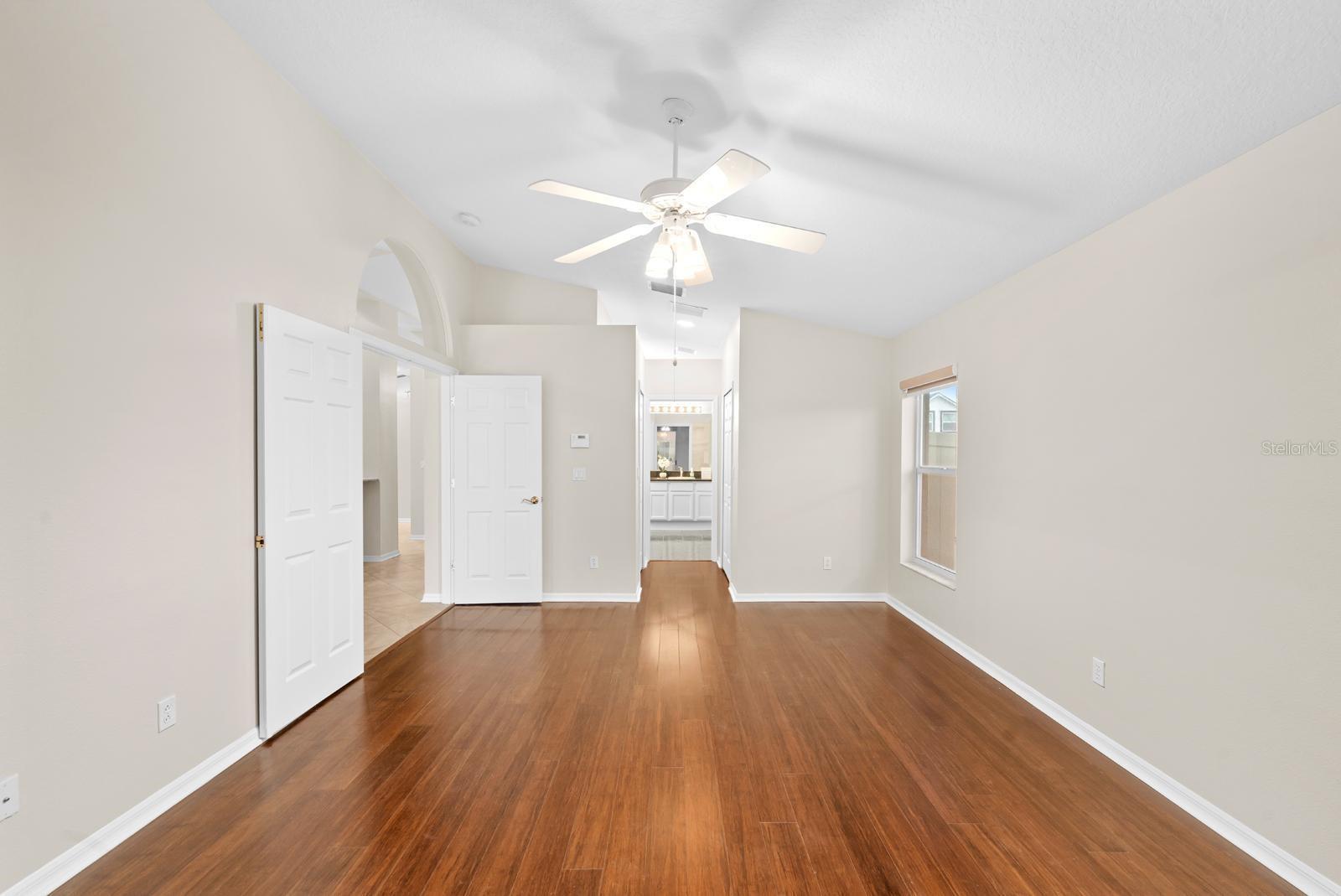 The primary bedroom features a double-door entry, bamboo wood flooring, a lighted ceiling fan, windows shades on every window, and TWO walk-in closets.