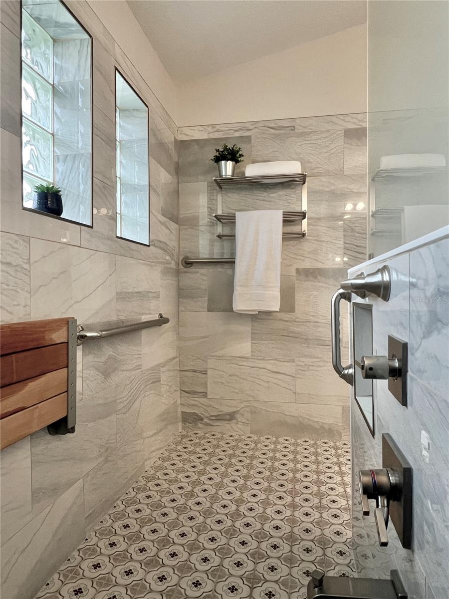 Massive walk-in shower (2022) (ADA compliant) with handicap access, grab bars, and a fold-up bench.  Features 4 windows, a rain shower head, and a tub spout!