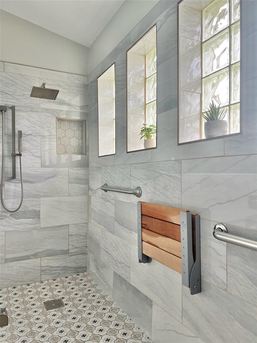 Massive walk-in shower (2022) (ADA compliant) with handicap access, grab bars, and a fold-up bench.  Features 4 windows, a rain shower head, and a tub spout!