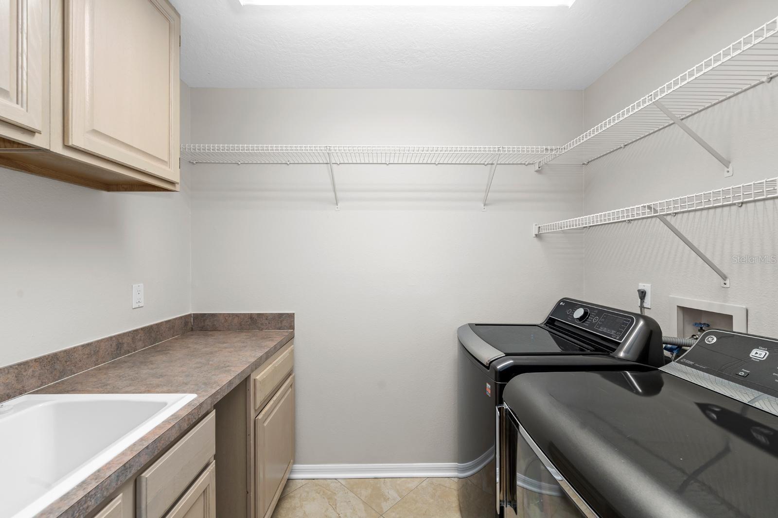 The laundry room features cabinets, folding space, storage shelves, and a utility sink.