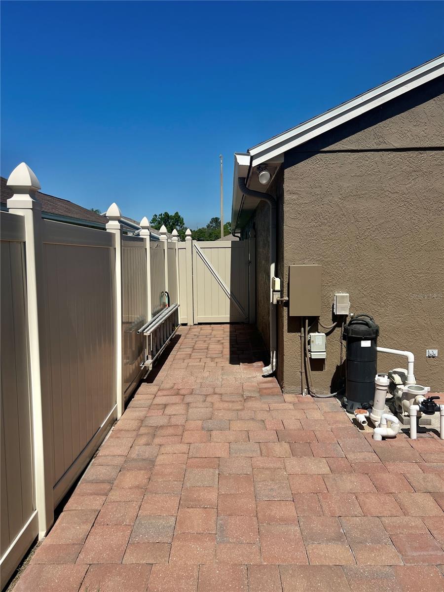 Pavered area and pool equipment next to the pool screen.