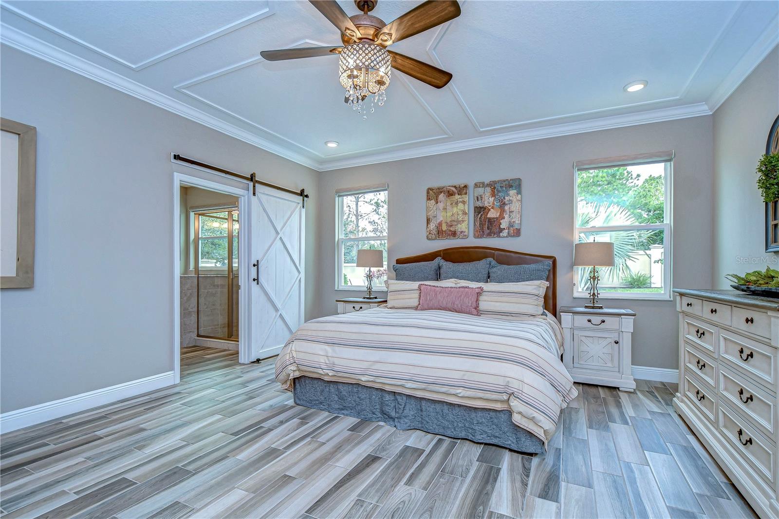 Unwind in this serene primary bedroom, boasting stylish barn doors and natural light that creates a calming retreat.