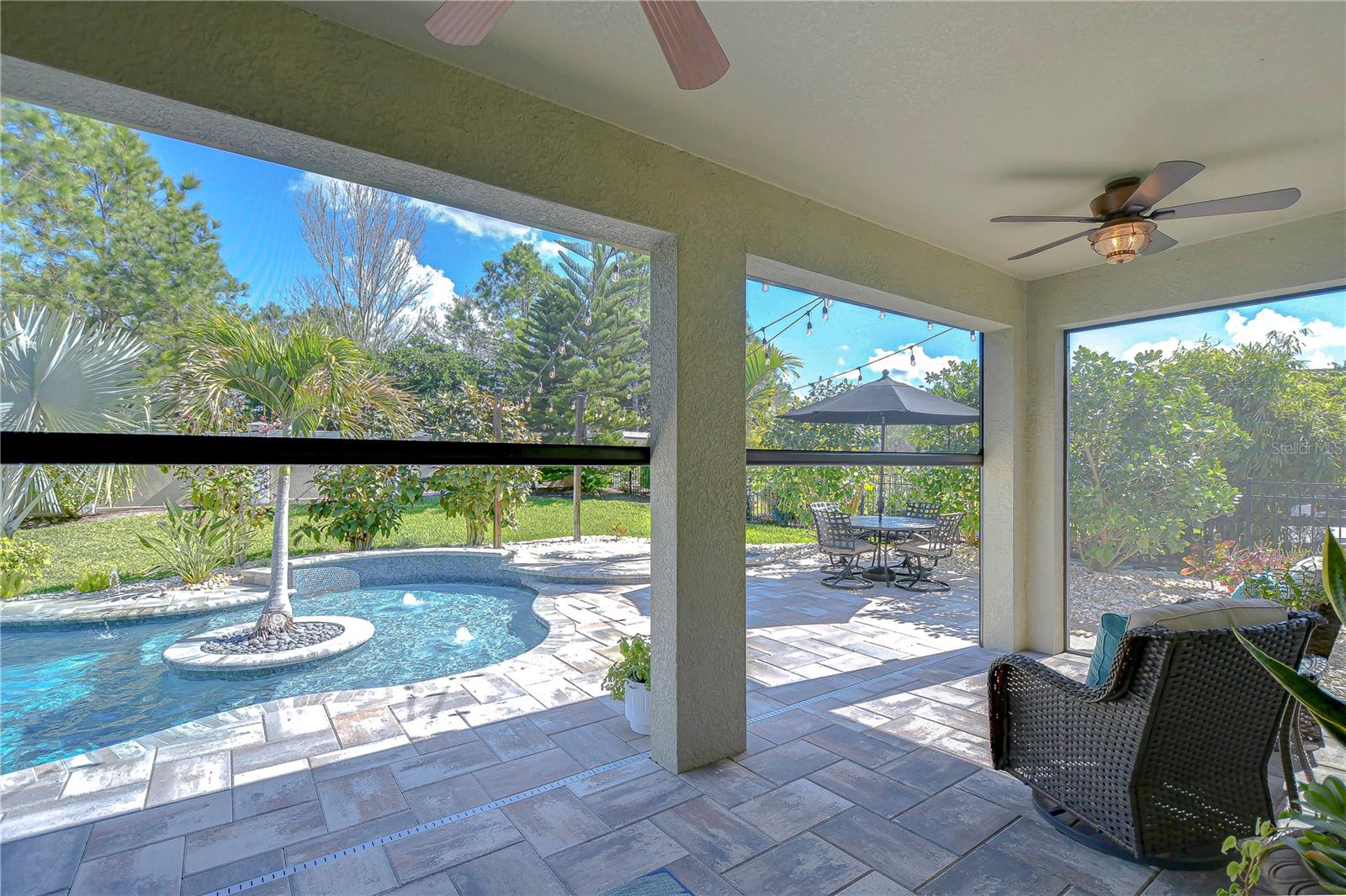 Step into your personal paradise with this splendid remote control screened patio overlooking a tranquil pool.