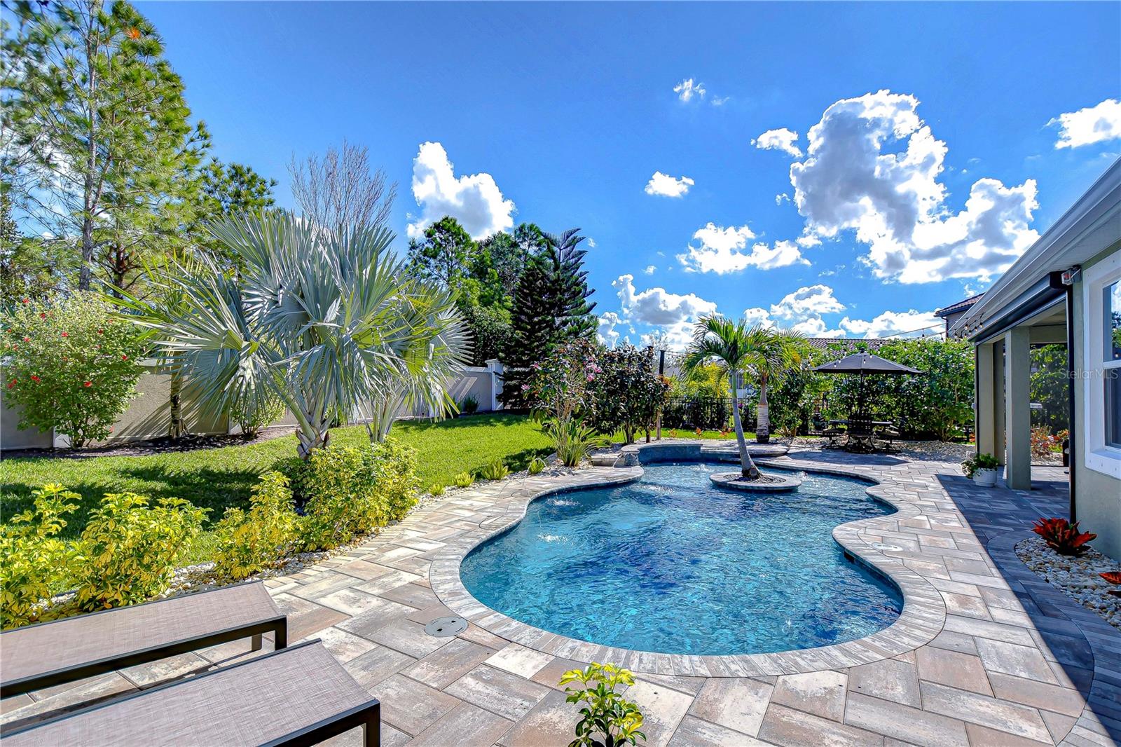 This stunning backyard oasis offers a pool and lush landscaping, perfect for enjoying sunny days.