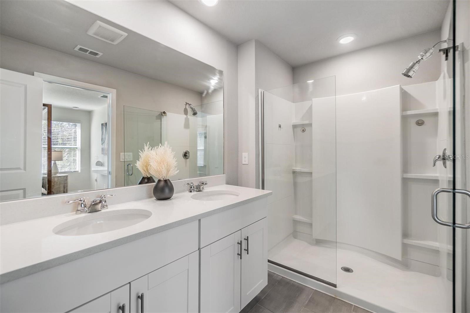 primary ensuite bathroom with dual vanities & newer glass door