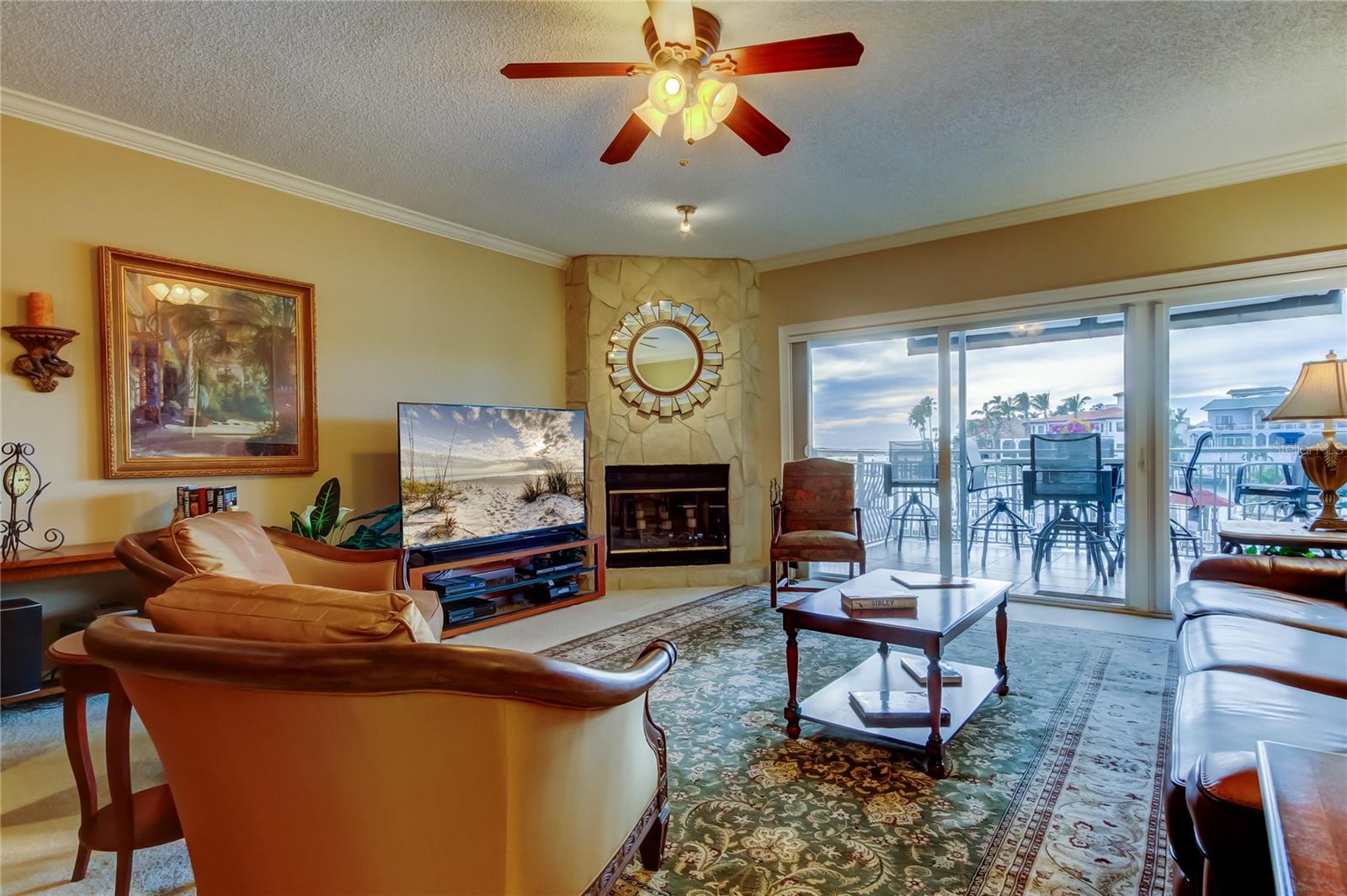 A cozy and elegant living room featuring a warm fireplace, stylish furnishings, and large sliding doors that open to a scenic waterfront view.