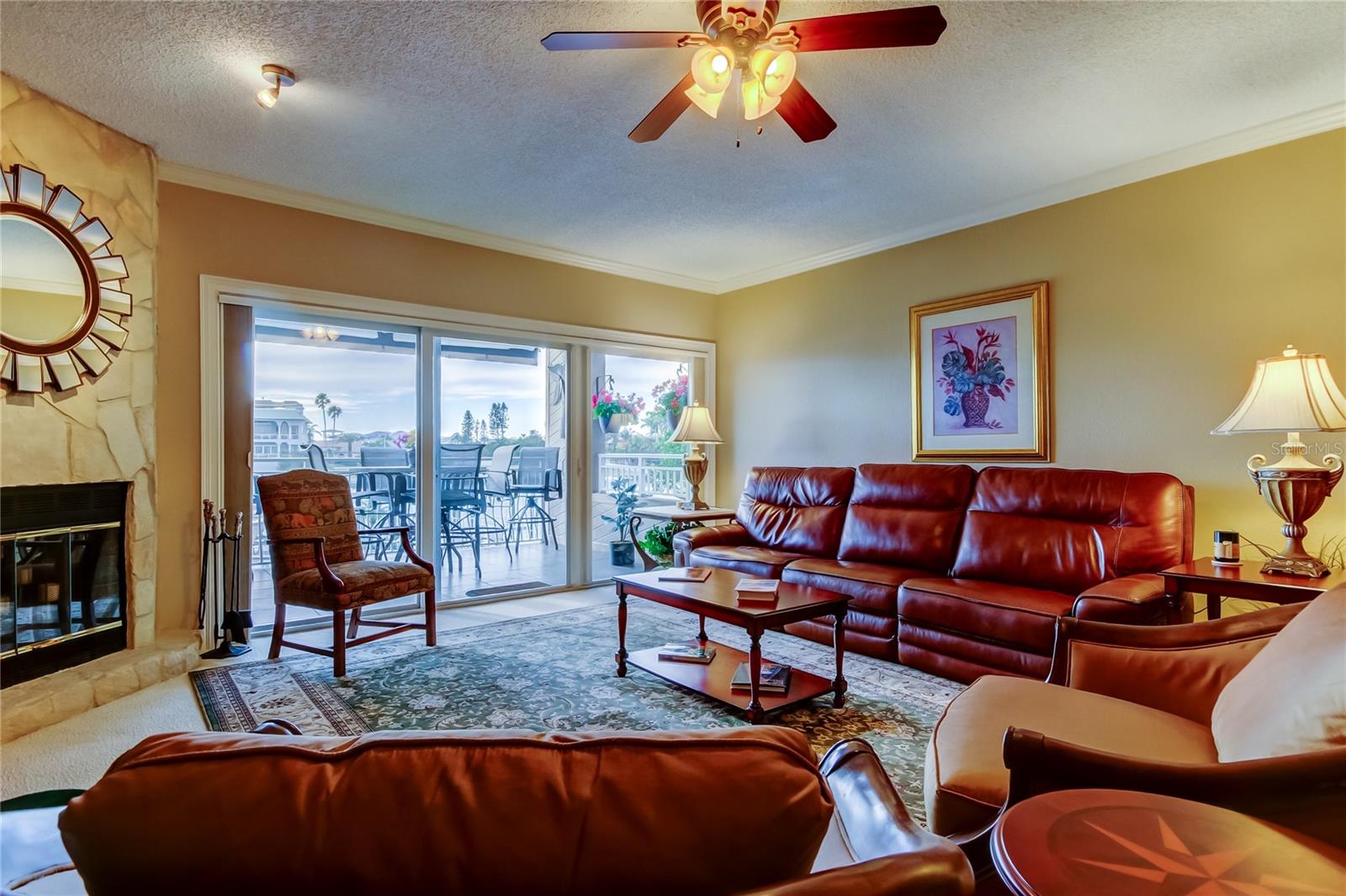 Yet another view of the living room, highlighting its spacious layout as seen from the dining area and kitchen, with a cozy fireplace and large sliding doors leading to the waterfront deck.