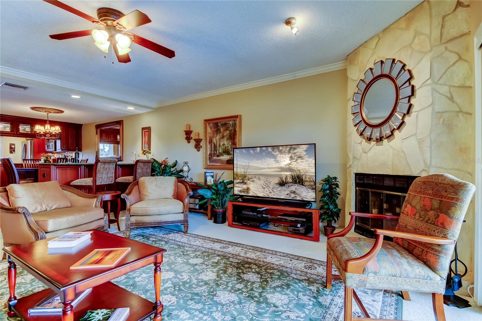 A view of the dining area and kitchen from the living room, showcasing an open-concept layout with warm lighting, elegant furnishings, and a cozy fireplace for a welcoming ambiance.