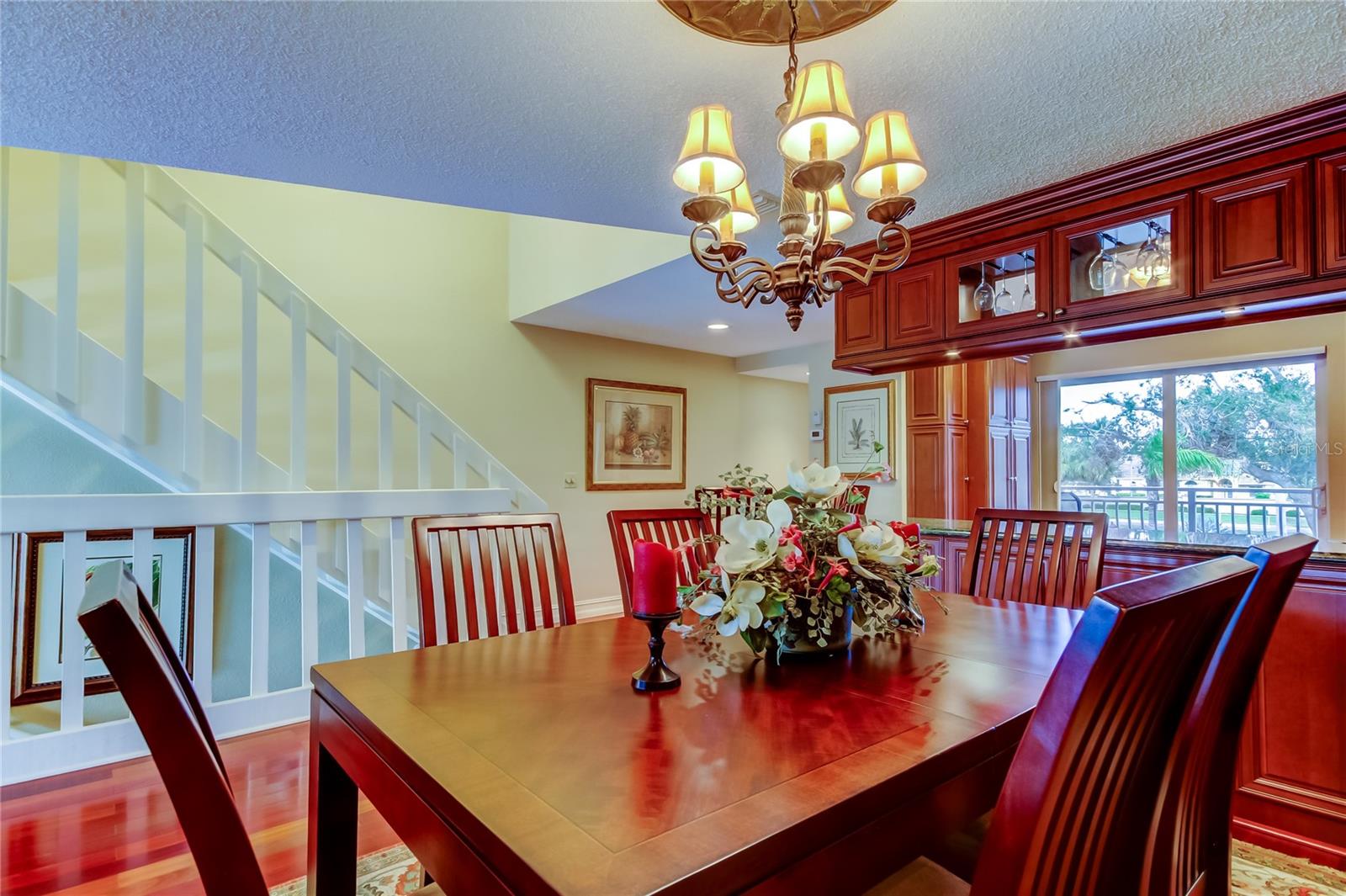 An inviting dining space with a rich wood table, elegant chandelier, and a seamless flow into the beautifully designed kitchen