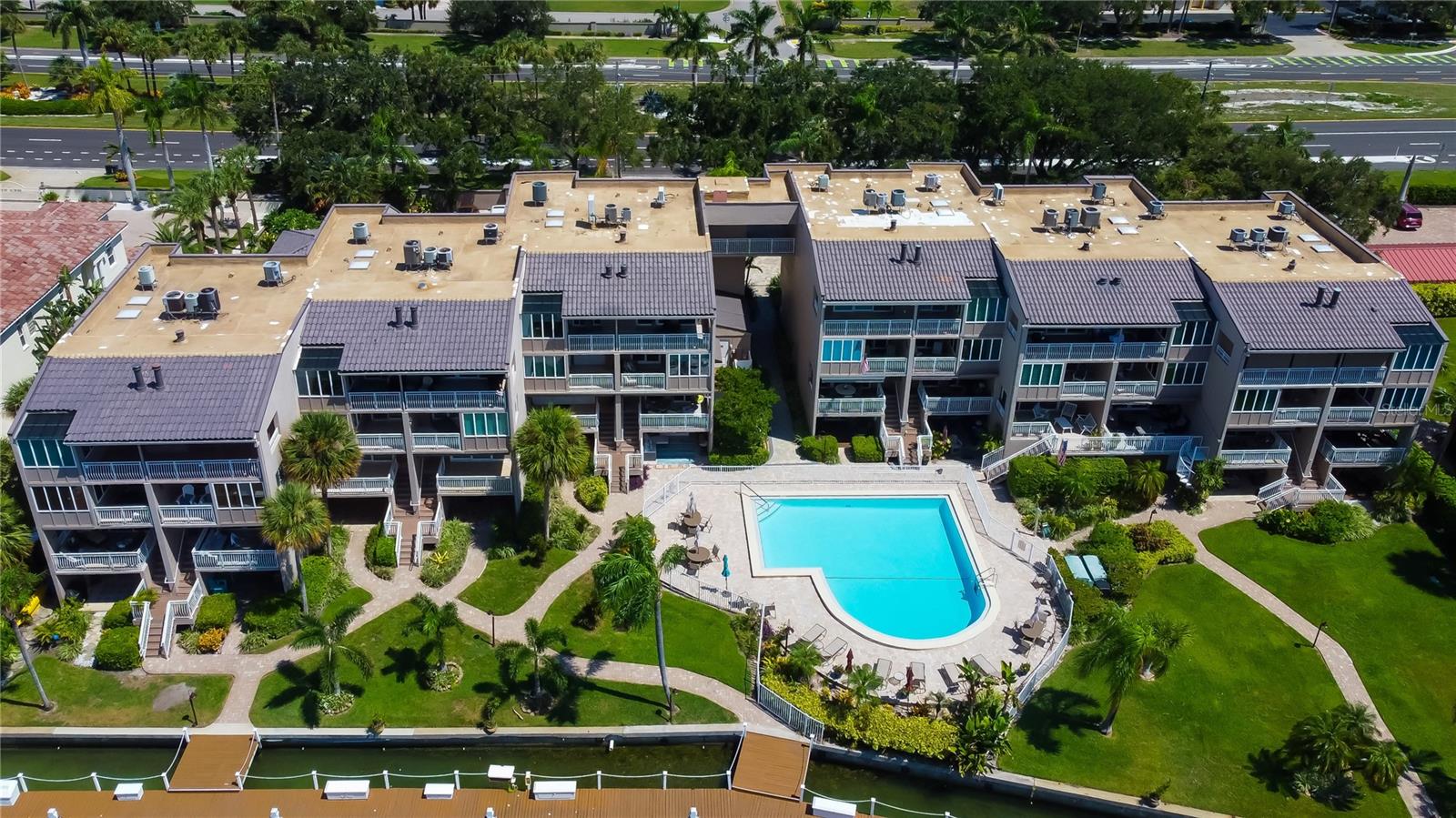 An aerial view of the beautiful waterfront Castillo Del Sol neighborhood, featuring modern townhomes, lush green spaces, and a stunning resort-style pool.