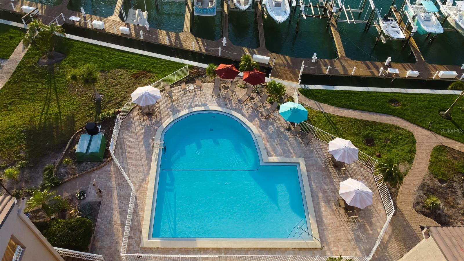 An aerial view of the Castillo Del Sol neighborhood pool area, overlooking the marina. Some landscaped sections have been identified for upcoming enhancements to further beautify the community.