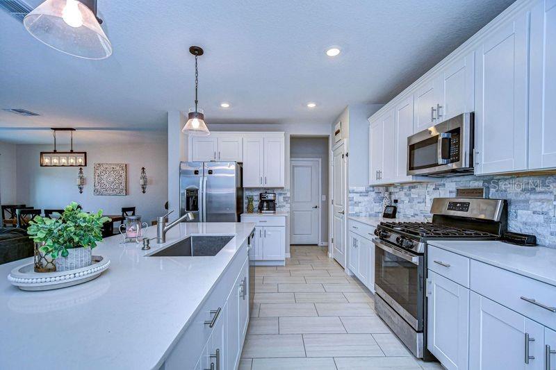 Long view of kitchen toward walk in pantry and laundry room.